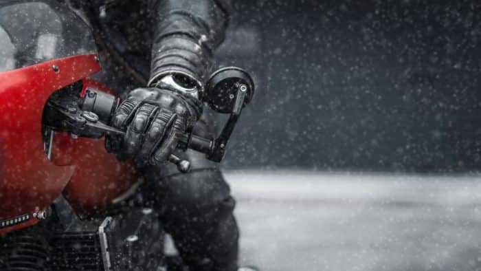 main de motard avec un gant et une moto rouge sous la pluie 