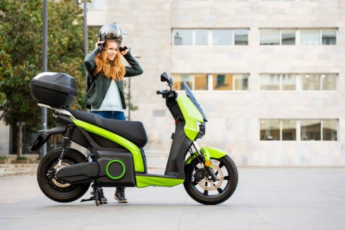 Femme avec casque et scooter électrique vert 